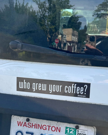 Car window with a sticker reading 'who grew your coffee?' and a Washington state license plate.
